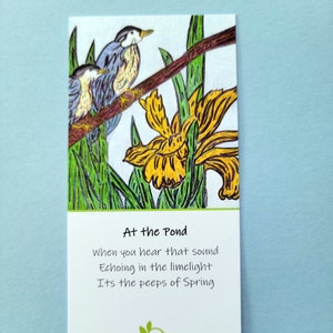 Shown Above: A bookmark with a yellow bog iris and two blue nuthatch birds on a branch. The text on the bookmark reads: "At the Pond, When you hear that sound, Echoing in the limelight, Its the peeps of Spring."