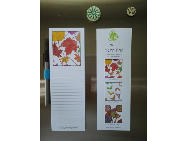 May include: Two rectangular fall-themed notepads with colorful maple leaf illustrations. One notepad has lined pages and a pen attached. The other notepad says "Fall Note Pad" and features three leaf design variations.