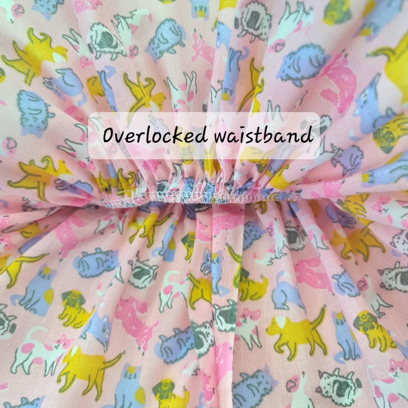 May include: Close-up of a pink fabric with a pattern of colorful cartoon animals. The fabric has an overlocked waistband. The text "Overlocked waistband" is visible on the image.