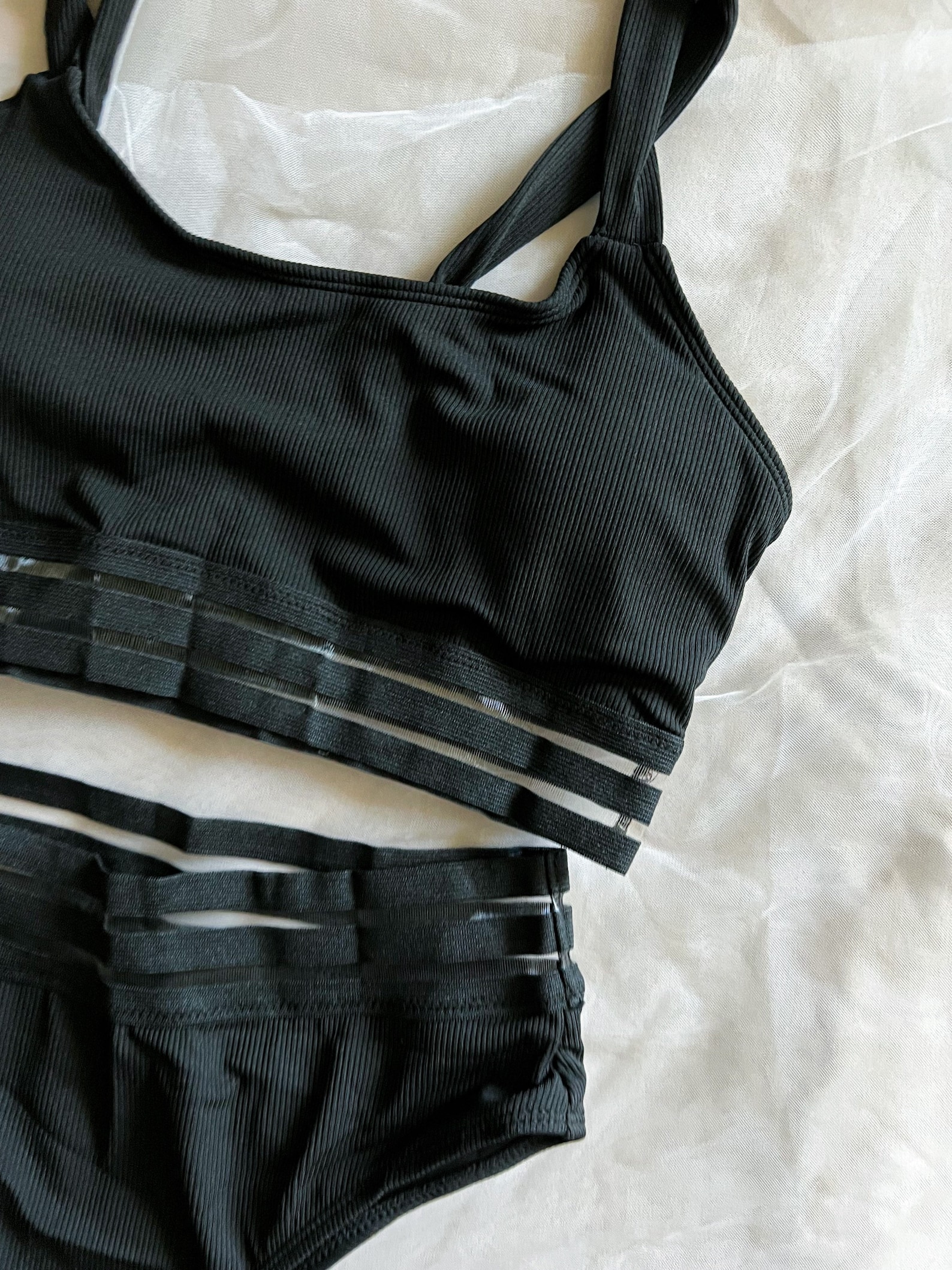 Close-up of a ribbed black goth swimsuit with sheer striped bands on a bralette top and high-waisted bikini bottom.