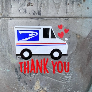 K&ouml;nnte beinhalten: Ein wei&szlig;er USPS-Postwagen mit einem blau-roten Logo und drei roten Herzen dar&uuml;ber. Die Worte "DANKE" sind in rot unter dem Wagen geschrieben.
