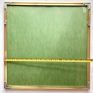 May include: A gold-coloured picture frame with a green mount and a measuring tape across the bottom. The frame is 45.7 cm wide.