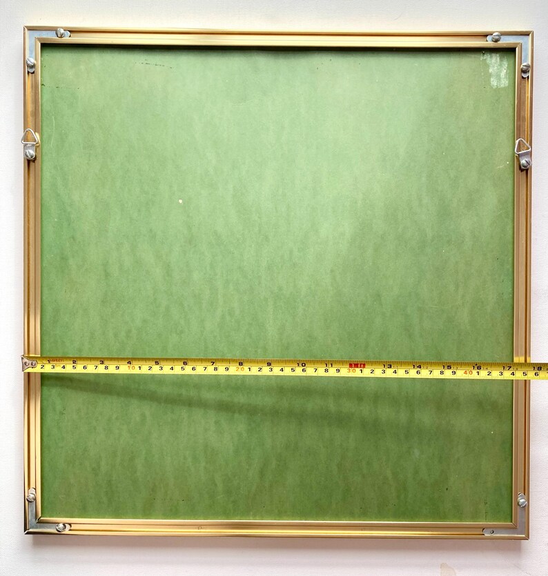May include: A gold-coloured picture frame with a green mount and a measuring tape across the bottom. The frame is 45.7 cm wide.