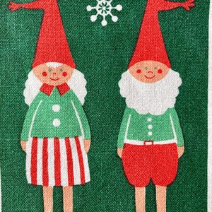 Puede incluir: Una tela verde con un patrón repetido de dos gnomos de dibujos animados y un copo de nieve. Los gnomos tienen sombreros rojos, camisas verdes y pantalones cortos rojos o una falda a rayas rojas y blancas. El fondo es verde oscuro.