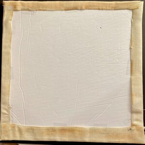 May include: A white canvas with a beige fabric border. The fabric border has a label that reads "Made in Italy".