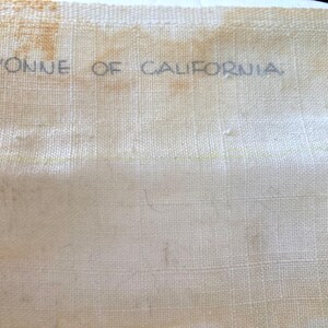 May include: A white fabric with the text "Yvonne of California" printed in black ink.