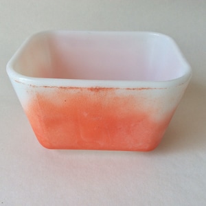 Puede incluir: Un plato cuadrado de vidrio blanco con un diseño degradado naranja. El plato tiene un aspecto vintage.