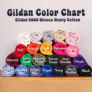 May include: A colour chart for Gildan 5000 Unisex Heavy Cotton apparel. The chart displays rolled fabric samples in colours including white, red, orange, and navy. The text "Gildan Colour Chart" is at the top.