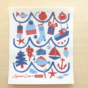 May include: A white kitchen towel with a blue and red nautical Christmas design. The design features a string of ornaments with a variety of nautical themes, including a sailboat, anchor, starfish, fish, and a stocking. The text "Square Love x KAUTZI" is printed in the bottom left corner.
