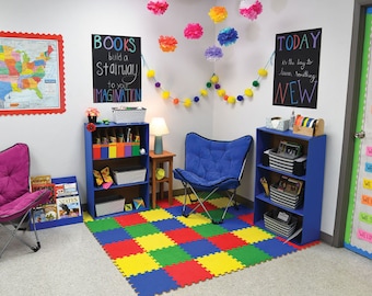 Puede incluir: Un rincón de lectura en un aula con un sillón de frijoles azul y morado, una estantería azul con libros y cestas, una pizarra negra con el texto "BOOKS build a Stairway to your IMAGINATION" y "TODAY is the day to learn something NEW", y una alfombra de colores.