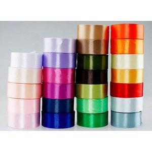 May include: Assortment of satin ribbon spools in various colors, including white, lavender, pink, red, navy blue, green, brown, orange, and beige.