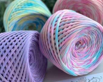 May include: Four colorful yarn skeins in pastel shades of pink, blue, yellow, and purple. The yarn is tightly wound, showing a woven texture. The image includes a label with the brand name "BARWA" and the text "yarn made in Ukraine."