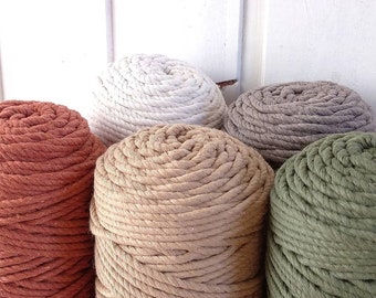 May include: Five spools of thick cotton rope in various colors, including natural, brown, rust, gray, and green. The spools are arranged in a row, with the natural spool in the center.