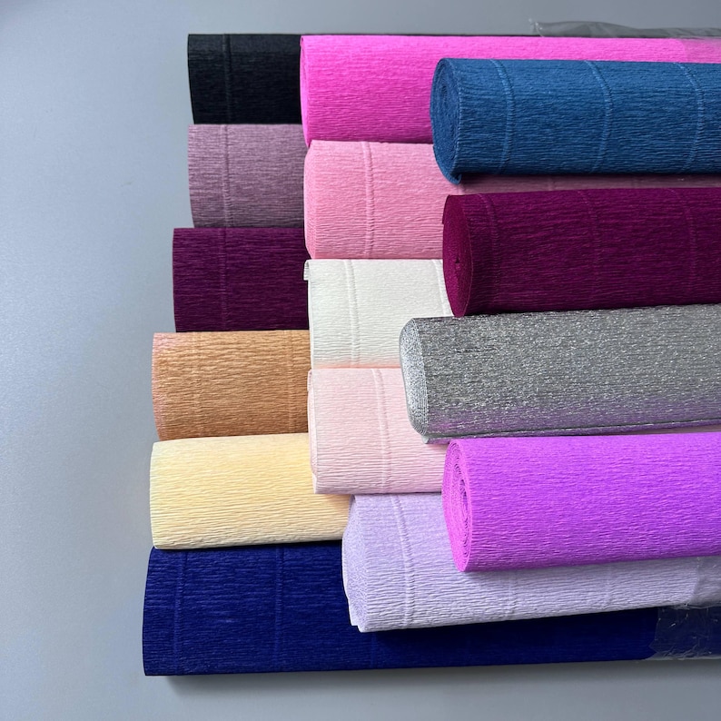 Close-up of vibrant crepe paper rolls in pink, lime green, yellow and other bright colors showing the textured surface