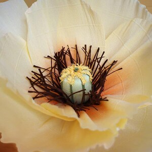 Close-up of the center of a giant handmade crepe paper poppy flower in cream and yellow tones, detailed realistic stamens and Italian crepe paper texture.