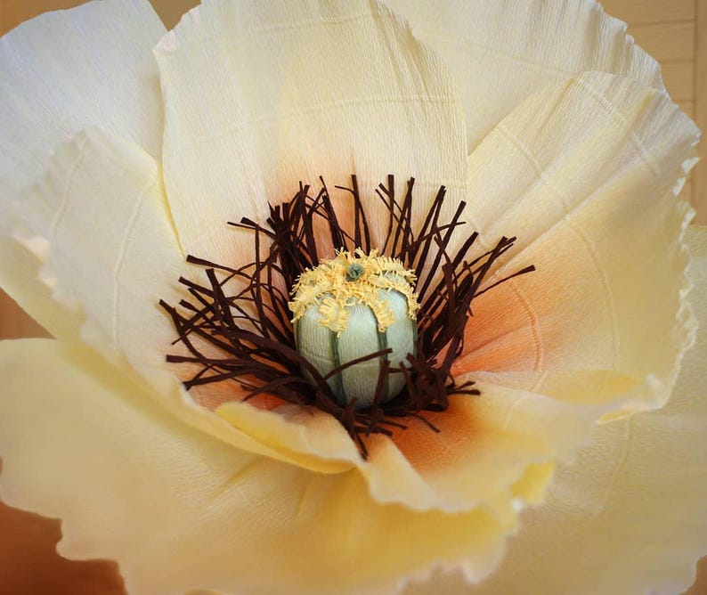 Close-up of the center of a giant handmade crepe paper poppy flower in cream and yellow tones, detailed realistic stamens and Italian crepe paper texture.