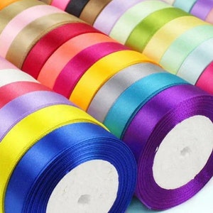 May include: A collection of colorful satin ribbon spools in various shades, including purple, blue, yellow, orange, red, pink, and green. The ribbons are arranged in a circular pattern, with the ends of the ribbons overlapping.