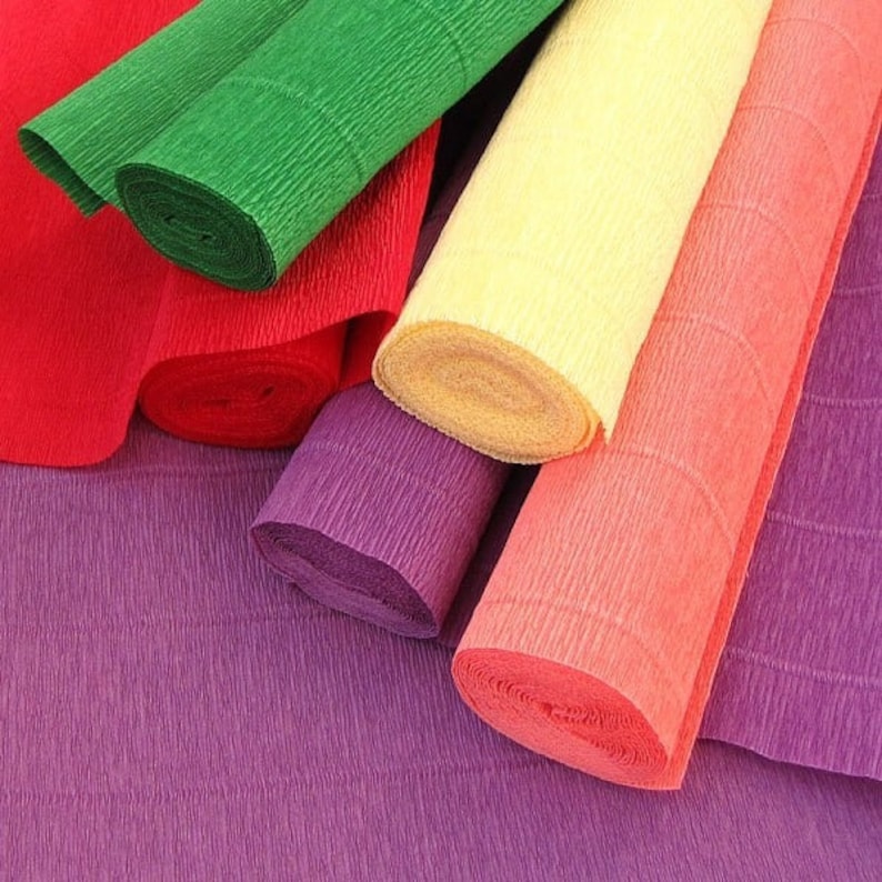 Large selection of colorful crepe paper rolls in various bright shades neatly arranged and packaged on a wooden surface