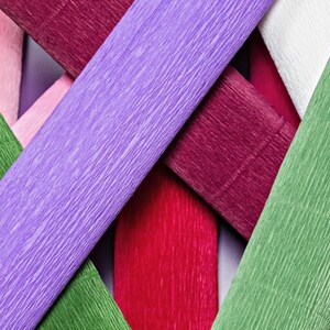 Pu&ograve; includere: Assortimento di carta crespa colorata in tonalit&agrave; di rosa, rosso, verde, viola e bianco. La carta &egrave; disposta a croce, mostrando la texture e le tonalit&agrave; vibranti.