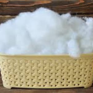 May include: A white, fluffy, fiberfill stuffing in a beige plastic basket with a woven pattern.