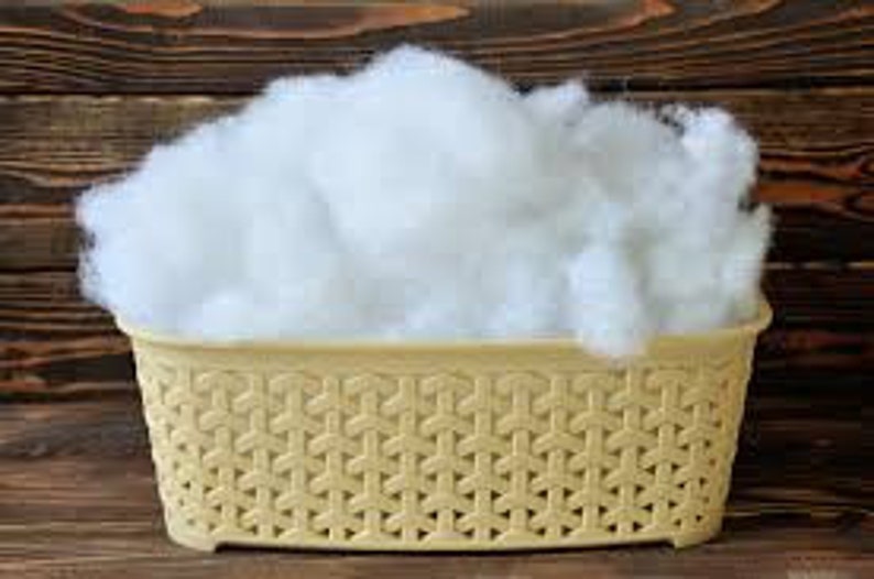 May include: A white, fluffy, fiberfill stuffing in a beige plastic basket with a woven pattern.