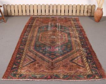 May include: A rectangular area rug featuring a central hexagonal medallion in shades of rust orange, deep teal, and muted pink. The rug displays intricate geometric patterns and floral motifs throughout, finished with a short fringe on both ends.