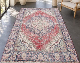 May include: A rectangular area rug featuring a central medallion design in shades of red, navy blue, and cream. The rug displays an intricate floral pattern throughout the field and a wide decorative border with repeating motifs and fringed edges.