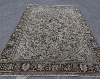 Könnte beinhalten: Ein rechteckiger Teppich mit einem zentralen Medaillon und komplexen geometrischen sowie floralen Mustern in Braun-, Beige- und gedämpften Salbeigrüntönen. Der Teppich hat eine breite, detaillierte Bordüre mit wiederkehrenden Motiven und Fransen.