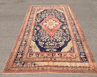 May include: A rectangular area rug featuring a deep navy blue central field with a large, intricate coral-colored medallion. The rug is decorated with floral motifs and geometric patterns, framed by multiple ornate borders in shades of tan, coral, and blue.