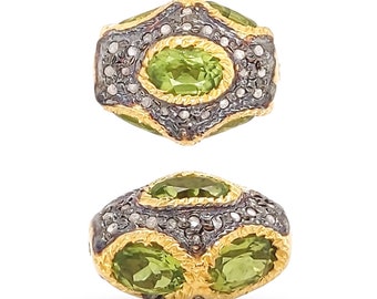 May include: A green gemstone bead with a gold and silver setting. The bead is oval shaped and has a faceted design. The bead is surrounded by small diamonds.