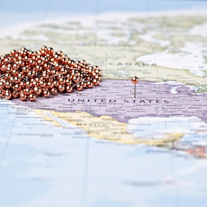 Op de afbeelding: Een kaart van Noord-Amerika met een cluster van koperkleurige punaises en een enkele punaise die een locatie in de Verenigde Staten markeert. De punaises zijn ideaal voor het markeren van bestemmingen of het plannen van reisroutes.