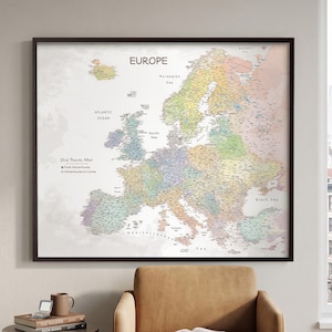 May include: A framed wall map of Europe featuring a pastel colour palette for individual countries, with the text "EUROPE" at the top and "OUR TRAVEL MAP" with a legend for "Past Adventures" and "Adventures to Come" on the left side.