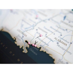 Puede incluir: Primer plano de un mapa del sur de los Estados Unidos con alfileres de colores rosa que marcan ubicaciones en Luisiana, Misisipi y Alabama. El mapa muestra las ciudades de Nueva Orleans, Biloxi, Hattiesburg, Meridian, Mobile, Montgomery y Columbus.