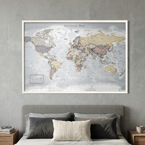 Puede incluir: Un mapa del mundo enmarcado titulado "Adventure Map" con una paleta de colores neutros. El mapa se muestra encima de una cama con almohadas y una mesita de noche. El texto "Life is a Journey Best Traveled Together" está en la esquina inferior izquierda.