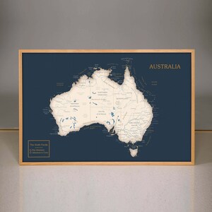 May include: A framed map of Australia with a navy blue background and white lines showing the states and territories. The map is titled "Australia" in gold lettering. The text "The Smith Family" is in the bottom left corner with two checkboxes labeled "Past Adventures" and "Adventures to Come".
