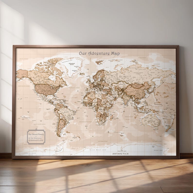 May include: A framed world map with a vintage aesthetic. The map is in shades of brown and beige, with detailed geographical features and country names. The title "Our Adventure Map" is at the top. The frame is a dark brown color.