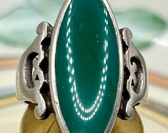 May include: A silver ring with a green oval-shaped stone set in a filigree design.