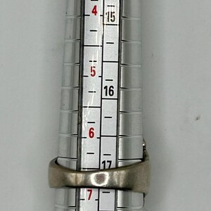 May include: A silver ring size gauge with markings from size 13 to 20. The gauge is used to measure the size of a ring.