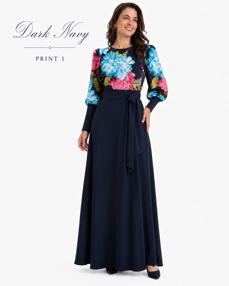 Puede incluir: Un vestido largo de color azul marino oscuro con un corpi&ntilde;o de estampado floral en tonos azules, rosas y verdes, mangas largas con pu&ntilde;os ajustados y una falda lisa con un cintur&oacute;n de lazo a juego. El texto Dark Navy PRINT 1 es visible.