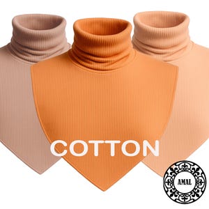 Op de afbeelding: Drie geribbelde coltrui-dickey's in tinten van gedempt roze, feloranje en licht perzik. Elk stuk heeft een puntige zoom en een hoge, geribbelde col. Het woord COTTON is in het wit gedrukt en een cirkelvormig logo bevat de tekst AMAL.