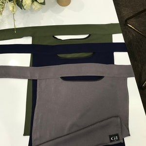 May include: Three fabric neck gaiters in different colors: olive green, navy blue, and gray. The gaiters have a small opening at the top and are labeled with the text "GII".
