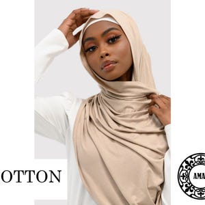 May include: A light beige cotton hijab with a simple, draped style. The hijab is made of a soft, comfortable fabric and is perfect for everyday wear.