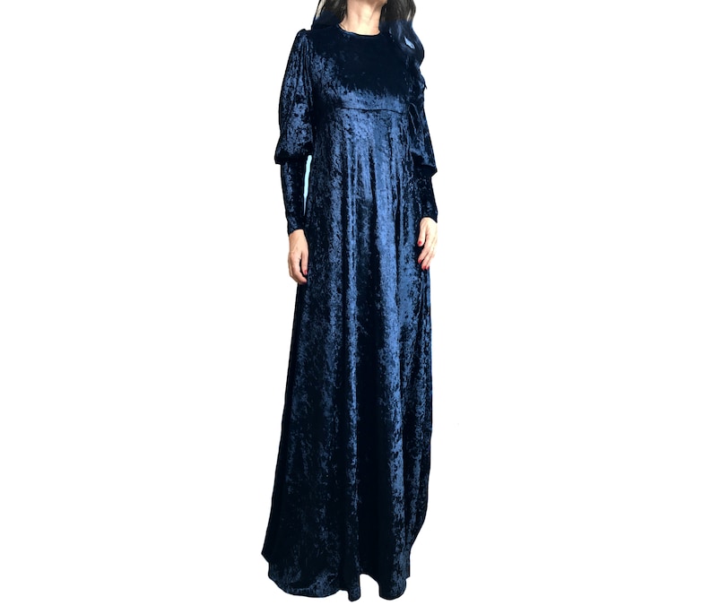 May include: A long, dark blue velvet dress with a gathered skirt and long sleeves. The dress has a slightly puffed sleeve detail.
