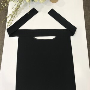 May include: Black fabric face mask with a small opening for the mouth and nose. The mask has two long straps that tie at the back of the head. The mask has a small black label with the text "GII" on it.