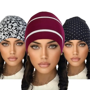 May include: Three women's headwear options: a black and white floral print, a burgundy striped beanie, and a black polka dot beanie.