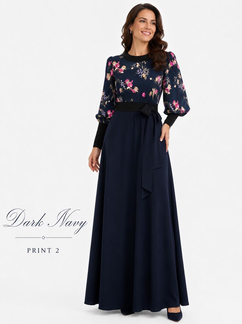 Puede incluir: Un vestido largo hasta el suelo en azul marino oscuro con estampado floral en el corpi&ntilde;o y mangas largas. La prenda incluye una falda azul marino lisa, cuello redondo negro, pu&ntilde;os negros y un cintur&oacute;n de tela a juego en la cintura. El texto dice Dark Navy PRINT 2.