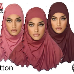 May include: Three cotton hijab head coverings in different shades of pink and burgundy. The hijabs have a ruffled edge and are made of a soft, stretchy fabric. The text "Made in the U.S.A." and "cotton" are visible in the image.