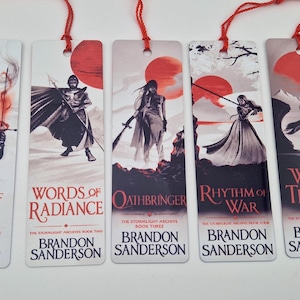 Puede incluir: Cinco marcapáginas rectangulares de papel con ilustraciones de la serie The Stormlight Archive de Brandon Sanderson. Cada uno muestra una escena con personajes, un sol rojo, el título del libro en rojo y una borla roja colgante.