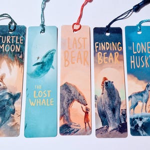 May include: Five colorful bookmarks with illustrations and text. The bookmarks feature images of a turtle, whale, polar bear, and husky. Each bookmark has a tassel at the top. The text on the bookmarks includes "Turtle Moon", "The Lost Whale", "The Last Bear", "Finding Bear", and "The Lone Husky".