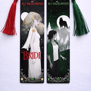 Może przedstawiać: Dwie prostokątne zakładki z frędzlami. Jedna przedstawia kobietę w białej sukni ze słowem "BRIDE" i wilkiem. Druga pokazuje kobietę w zielonej koszuli w kratę z wilkiem na górze. Obie mają nazwisko autora.